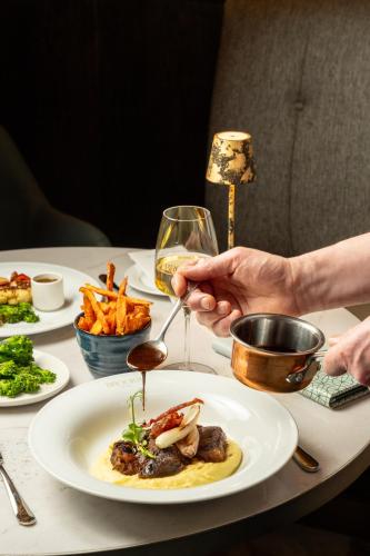 a table with a plate of food and a person holding a spoon at Brooks Hotel in Dublin