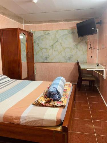 a bedroom with a bed and a desk with a television at Nhà Nghỉ Quỳnh Hương - Quynh Huong Hostel in Long Thành