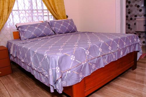 a bed with a purple comforter on top of it at Kindow Appart in Pointe-Noire