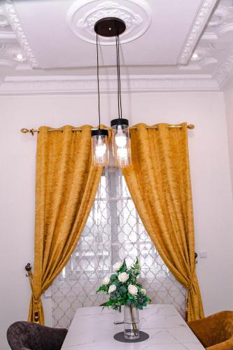 a dining table with yellow curtains and a vase of flowers at Kindow Appart in Pointe-Noire