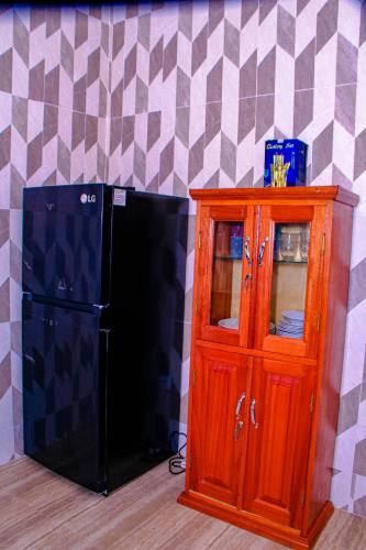 a black refrigerator and a wooden cabinet next to a wall at Kindow Appart in Pointe-Noire