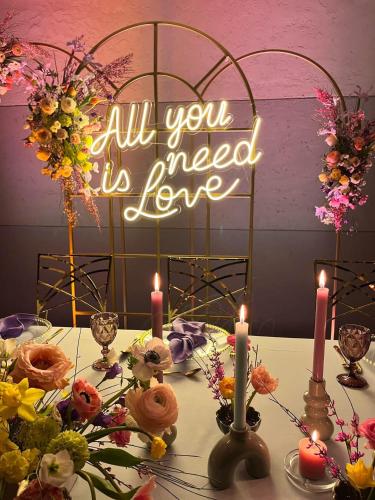 a table with candles and a sign that says all you need is love at Kraina Jezior in Ostróda