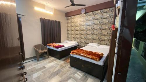 a bedroom with two beds and a brick wall at kashidham home stays in Varanasi