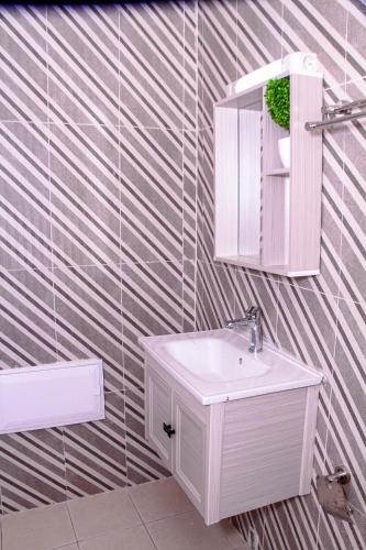 a bathroom with a white sink and a mirror at Kindow Appart in Pointe-Noire
