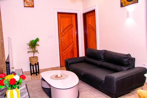 a living room with a black leather couch and a table at Kindow Appart in Pointe-Noire