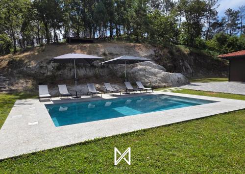 a swimming pool with lounge chairs and umbrellas at MyStay - Encosta da Barragem in Fafe