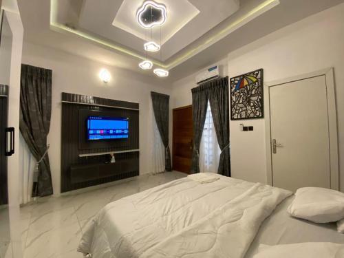 a bedroom with a bed and a flat screen tv at CecePlusShow in Lekki