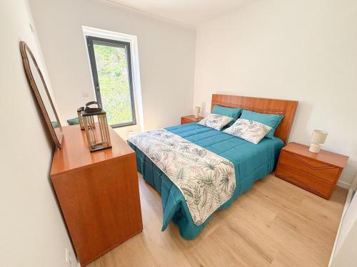 a bedroom with a bed and a dresser and a window at Casa Norbina in Ribeira Quente