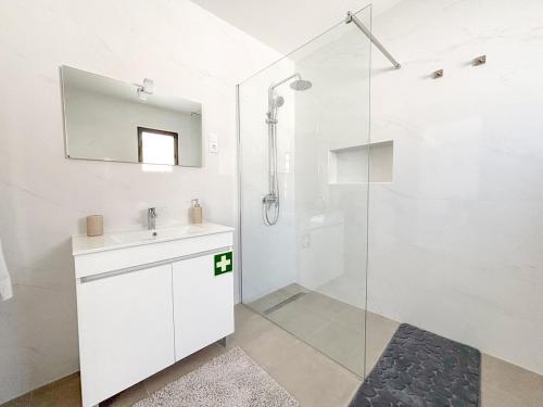 a white bathroom with a sink and a shower at Casa Norbina in Ribeira Quente