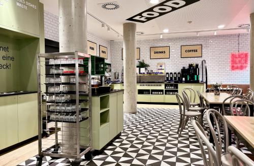 a restaurant with a counter with chairs and a table at MEININGER Hotel Wien Downtown Franz in Vienna