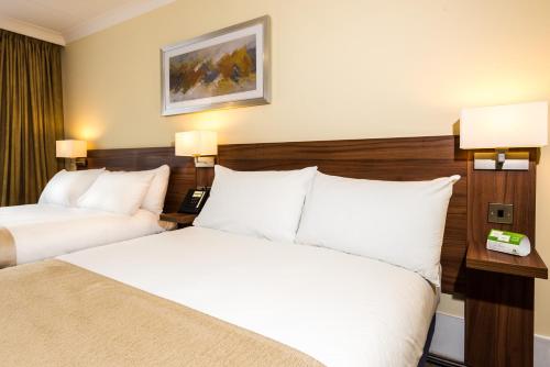 two beds in a hotel room with white pillows at Holiday Inn Stoke on Trent M6 Jct15 by IHG in Stoke on Trent