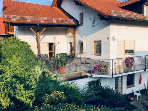 a white house with a balcony with flowers on it at Ferienwohnung Haus Veronika in Wegscheid