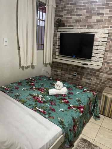 a bedroom with a bed with a blanket with flowers on it at Kitnet Adorável na sedede Aracruz ES 1KM do centro individual wifi cozinha equipada in Aracruz