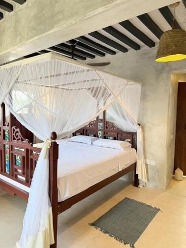 a bedroom with a canopy bed with mosquito net at Star House 3 in Shela