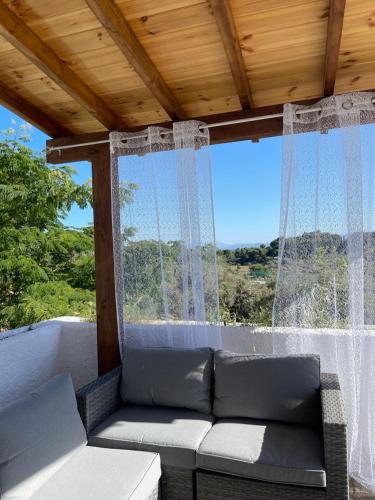 a couch sitting on a porch with a window at Rastoni Apartments Skiathos in Troulos
