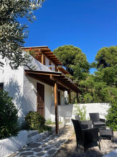 a white house with two chairs and a table at Rastoni Apartments Skiathos in Troulos
