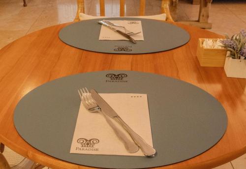 a table with two plates and a fork and knife at Paradise Hotel & Wellness in Saint Vincent
