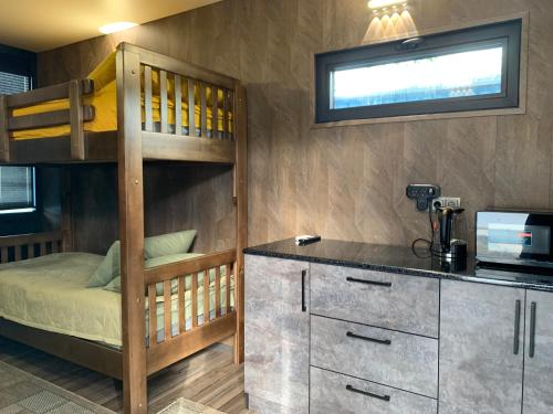 a bedroom with a bunk bed and a kitchen with a microwave at Hippo camp Karakol in Karakol