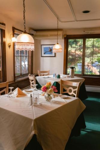 a dining room with two tables with flowers on them at Stonehurst Manor Breakfast & Dinner Included in North Conway