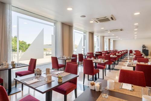 a restaurant with tables and chairs and a large window at Eurostars Plaza Acueducto in Segovia