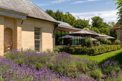 a garden with purple flowers in front of a building at Lucknam Park Hotel in Chippenham