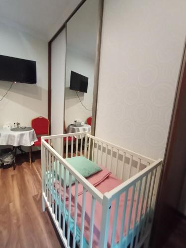 a crib in a room with a table and a mirror at Villa Varzob ll in Warsaw