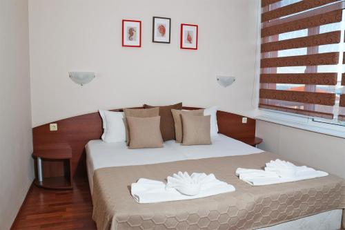 a bedroom with a bed with two towels on it at Red House Guest House in Nesebar