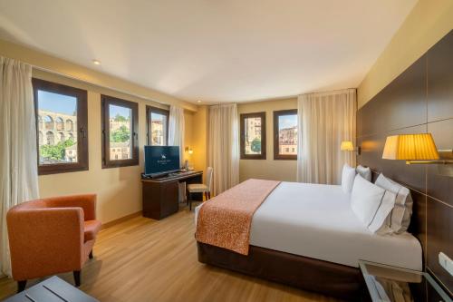 a hotel room with a bed and a desk at Eurostars Plaza Acueducto in Segovia