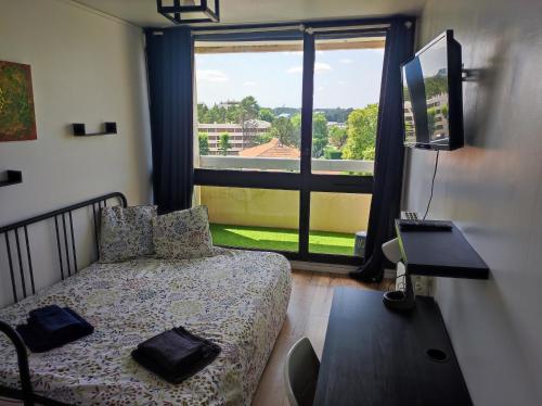 a bedroom with a bed and a large window at Appartement spacieux et lumineux, idéalement situé in Pessac