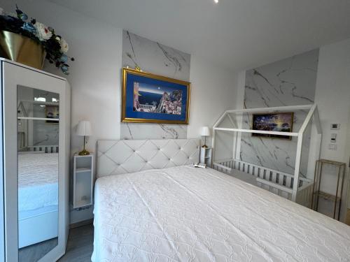 a bedroom with a white bed and a mirror at Szemesbay lakás B 101 in Balatonszemes