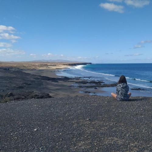a woman sitting on the beach looking at the ocean at Sunset in paradise in Cotillo