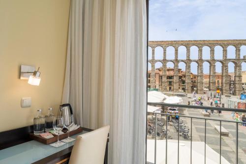 a room with a balcony with a view of the coliseum at Eurostars Plaza Acueducto in Segovia