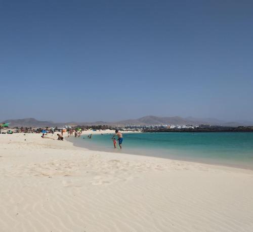 a group of people walking on a beach at Sunset in paradise in Cotillo