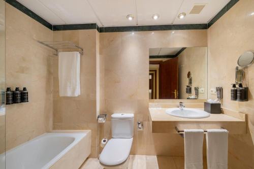a bathroom with a tub and a toilet and a sink at Eurostars Plaza Acueducto in Segovia