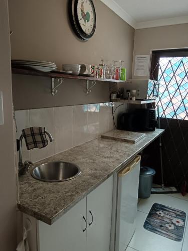 Una cocina con un fregadero y un reloj en la pared. en Studio On Fairway, en Langebaan