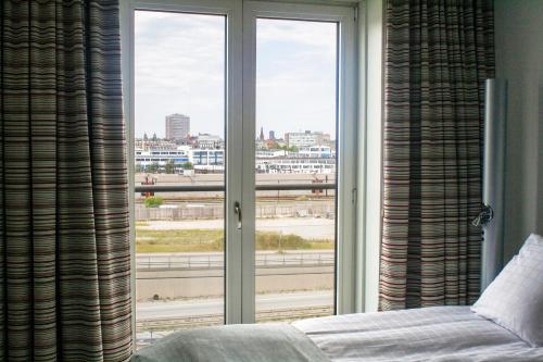 a bedroom with a window with a view of a city at Copenhagen Island Hotel in Copenhagen