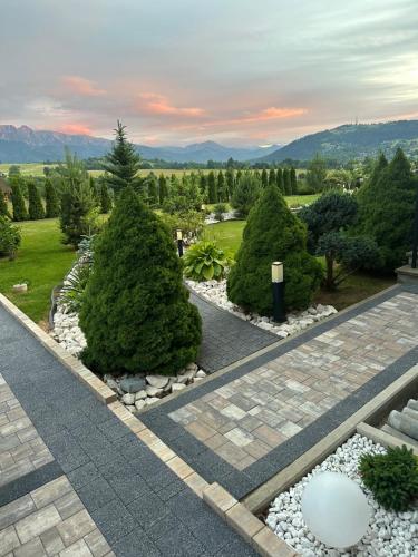 a garden with trees and rocks and a sunset at Willa Tatrzańska Zohylina in Poronin