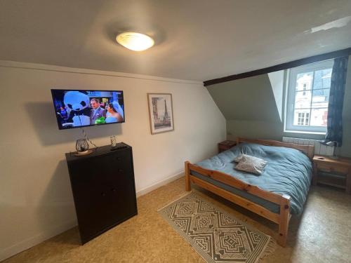 a bedroom with a bed and a tv on the wall at appartement, en plein coeur de Saint Pierre sur Dives in Saint-Pierre-sur-Dives