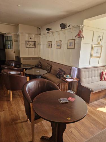 a living room with a couch and tables and chairs at The Swan Hotel Oxford in Eynsham
