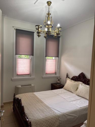 a bedroom with a bed with a chandelier and two windows at Korca Center Apartment in Korçë