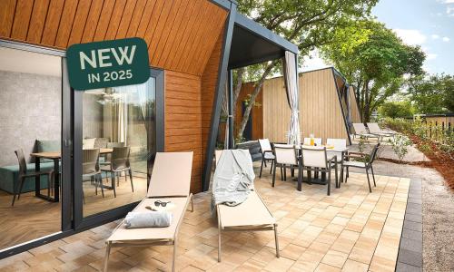 a patio with chairs and tables and a new in sign at Aminess Style Glamping Villas & Holiday Homes Atea in Njivice
