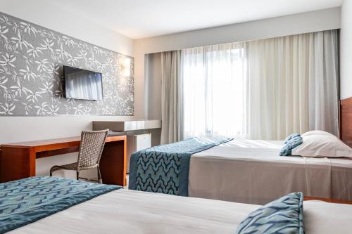 une chambre d'hôtel avec deux lits et un bureau dans l'établissement Rio Quente Resorts - Hotel Luupi, à Rio Quente