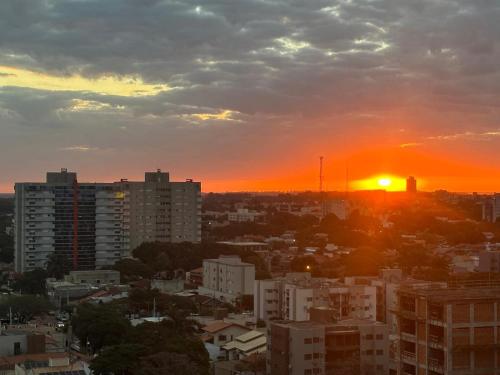 a city skyline with the sun setting in the sky at Apartarmento 2 Quartos in Dourados