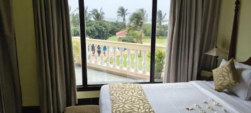 a hotel room with a bed and a large window at The Hans Coco Palms in Puri