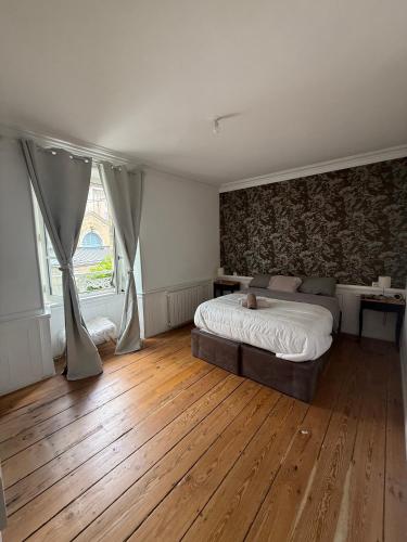Un dormitorio con una cama y suelo de madera. en L'ideal, en Vannes
