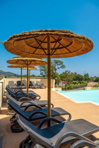 une rangée de chaises et de parasols à côté d'une piscine dans l'établissement Résidence Odalys San Martinu, à Sainte-Lucie de Porto-Vecchio