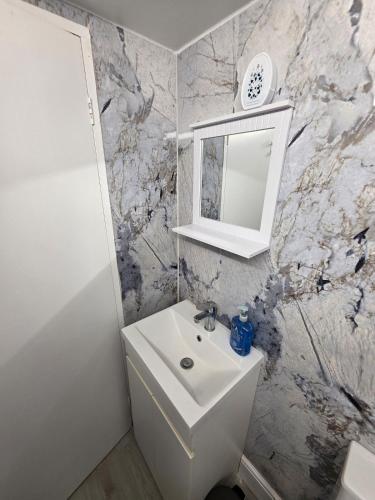 a white bathroom with a sink and a mirror at Private Basement Flat in London
