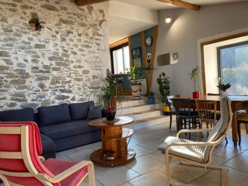 ein Wohnzimmer mit einer blauen Couch und einer Steinwand in der Unterkunft La Maison de Graviès in Anduze