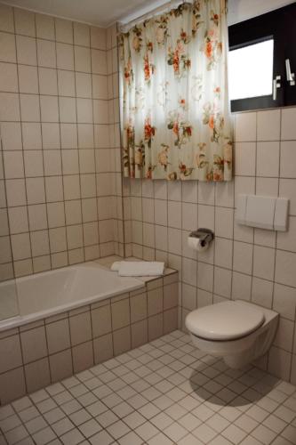 a bathroom with a tub and a toilet and a shower curtain at Hotel Cristal in Nürnberg