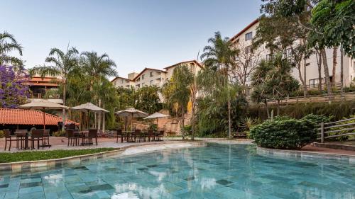 une piscine dans un complexe hôtelier avec tables et parasols dans l'établissement Rio Quente Resorts - Hotel Luupi, à Rio Quente
